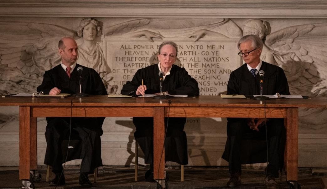 Kathleen Chalfant (center) in a scene from Waterwell's production of "The Courtroom: A Re-Enactment of Deportation Proceedings".